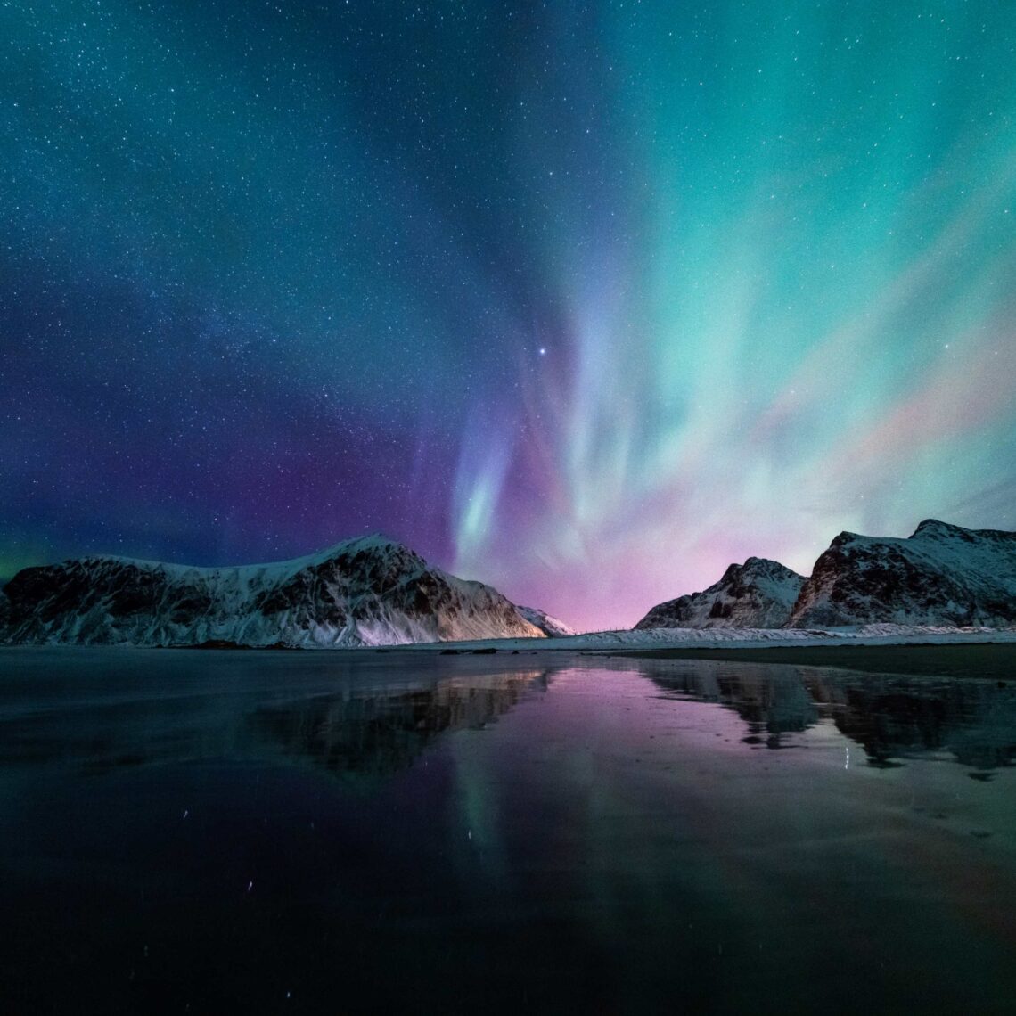 Arctic northern lights over water and icy hills.