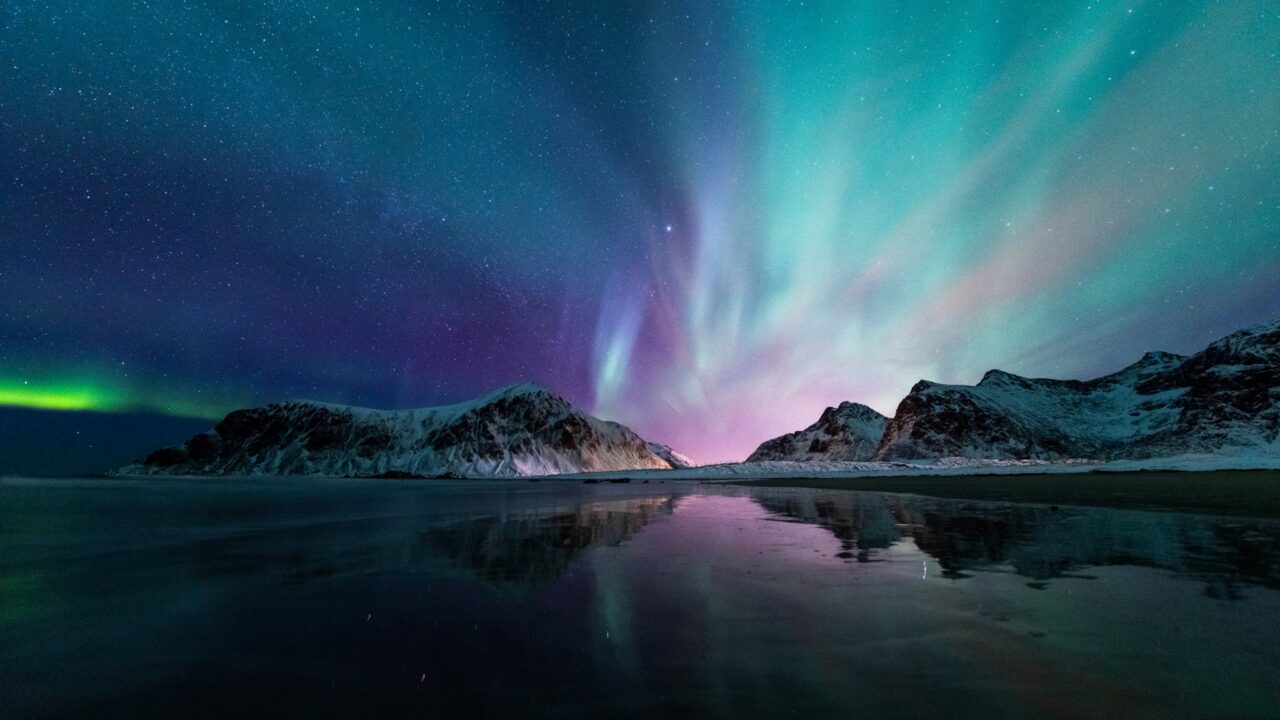 Arctic northern lights over water and icy hills.